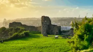 Ancient stone castle ruins set against a lush green field in East Sussex landscape.