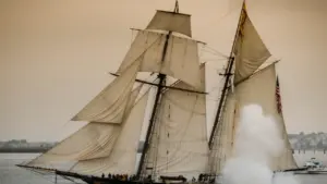 A historic wooden galleon ship sailing on open water under an overcast sky.