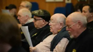 Group of volunteers sitting in a hall reading documents at a local meeting