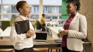Two professional women discussing business opportunities in a modern office working environment.