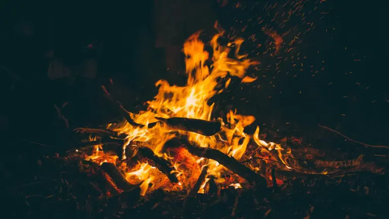 A glowing bonfire crackling at night in a UK setting, sparks flying upwards.