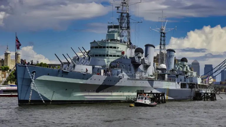 HMS Belfast docked on the River Thames in London with a Union Jack flag.
