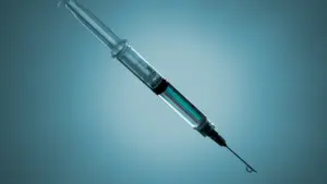 A close-up view of a medical syringe isolated on a blue background.