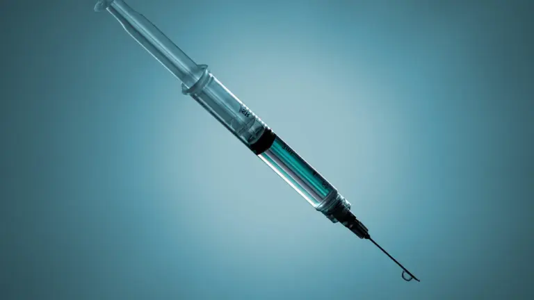 A close-up view of a medical syringe isolated on a blue background.